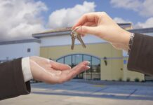 How A Mortgage Broker Can Help When Buying Business Property Real Estate Agent Handing Over the Keys in Front of Vacant Business Office.