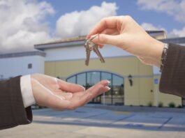 Real Estate Agent Handing Over the Keys in Front of Vacant Business Office.
