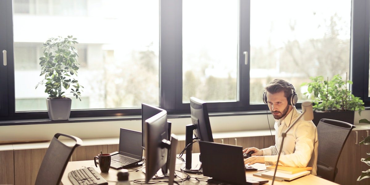 man with headphones working in an office next to a window