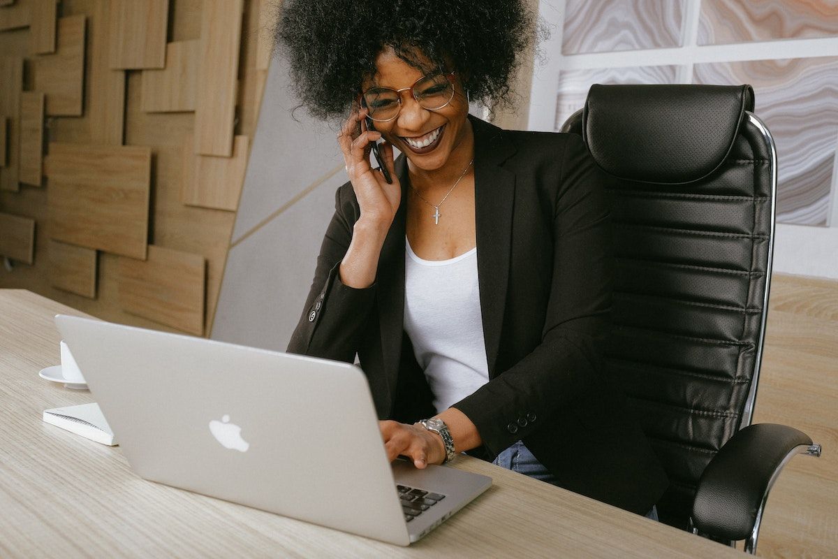 a woman typing on her laptop while talking on the phone